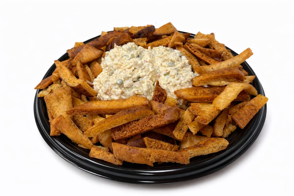 A black platter filled with golden-brown pita chips surrounding two mounds of creamy dip.