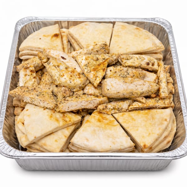 Catering tray filled with seasoned chicken pieces and pita bread triangles.