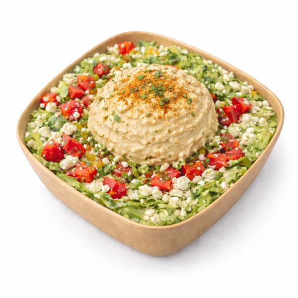 Hummus bowl with lettuce, tomatoes, feta cheese, and herbs in a brown container.