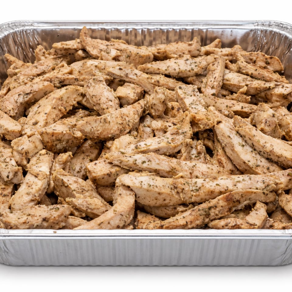 Seasoned chicken strips in a large aluminum catering pan, ready for serving.