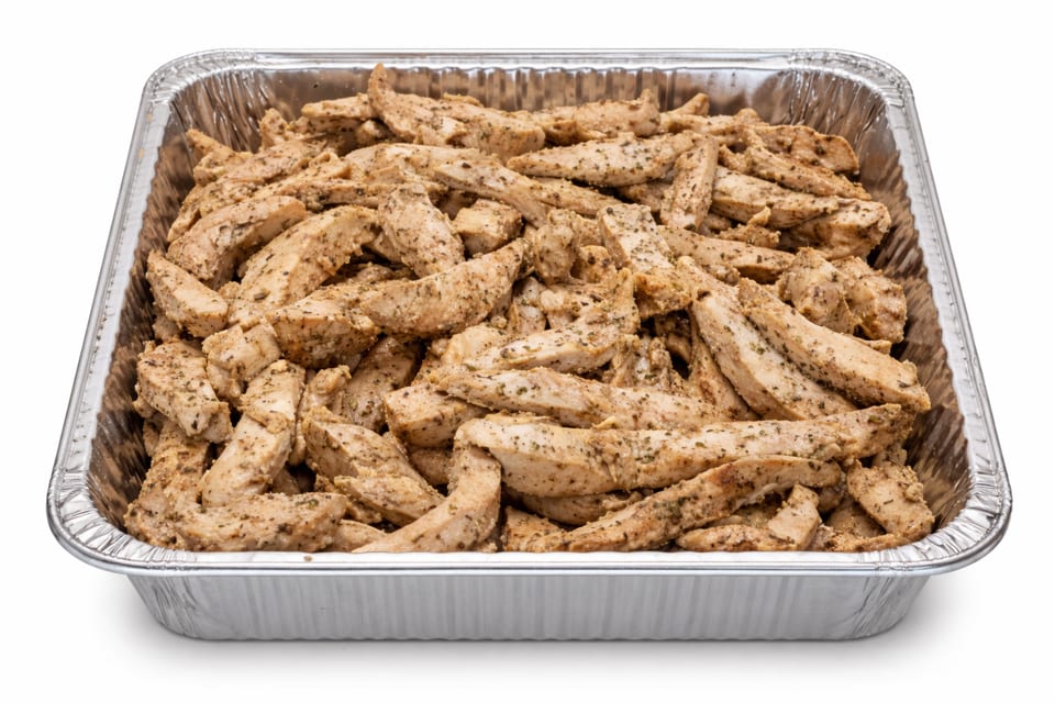 Seasoned chicken strips in a large aluminum catering pan, ready for serving.