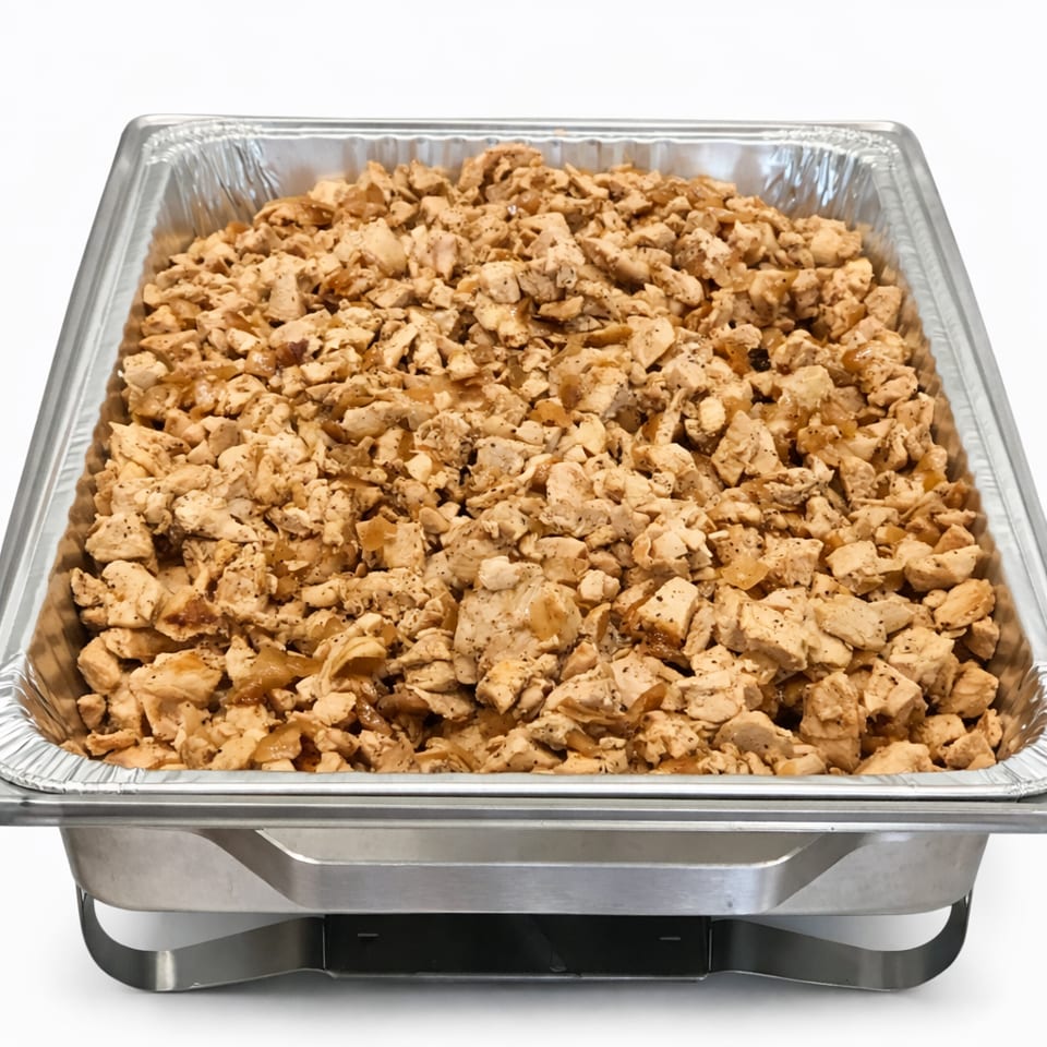 A catering pan filled with diced, seasoned chicken, ready for serving.